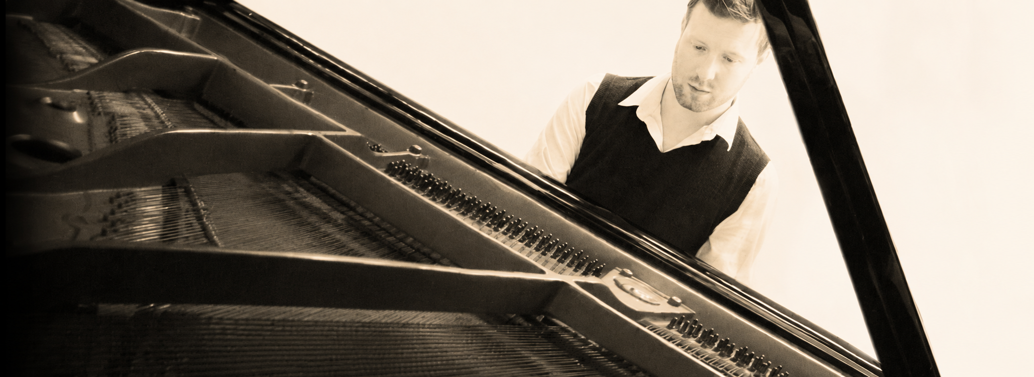 Rob Upton at a grand piano, in warm sepia tones